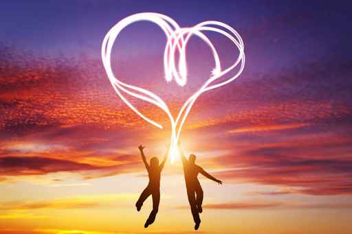 Happy couple in love jump making heart symbol of light